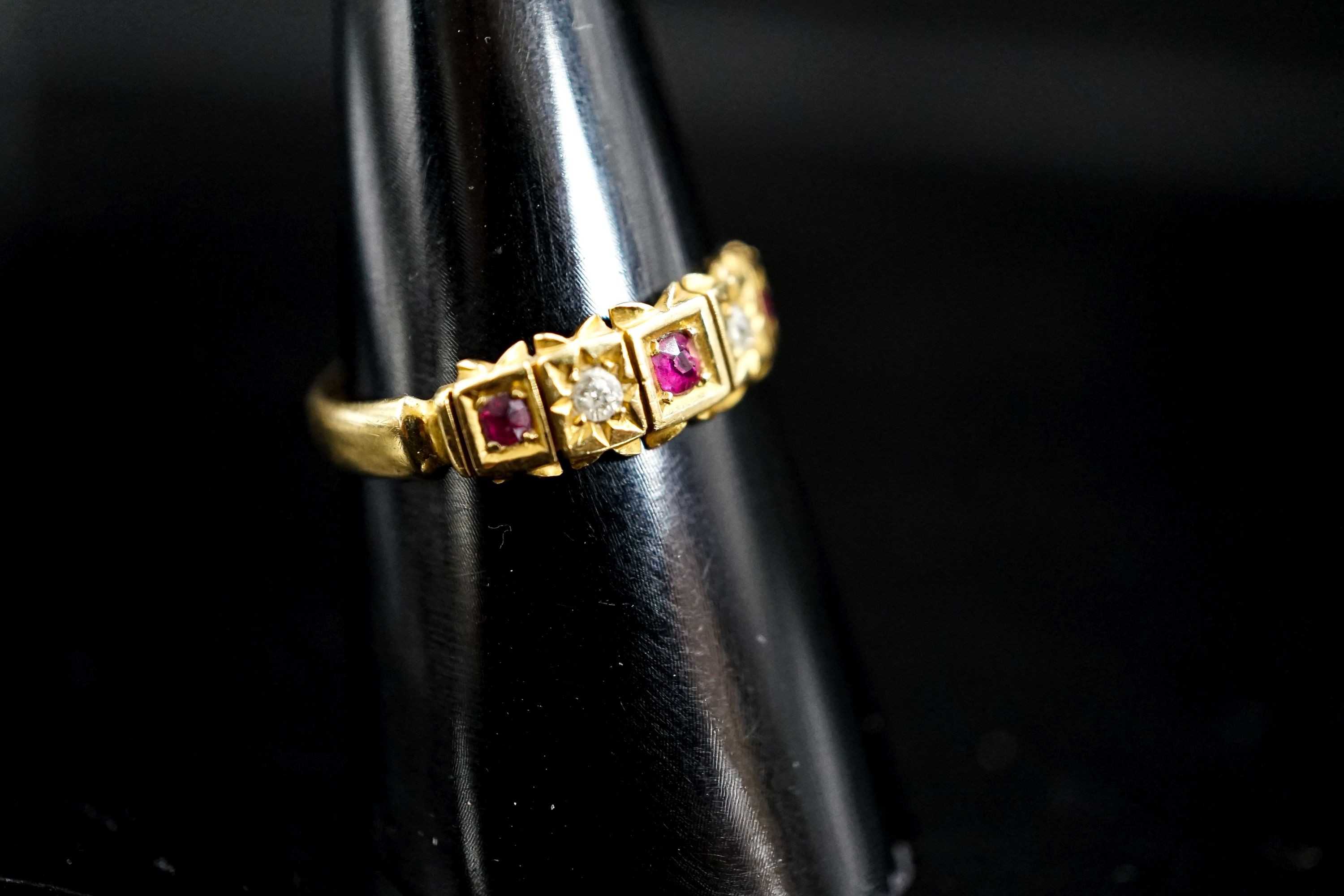 A late Victorian 18ct gold, ruby and diamond chip set half hoop ring, size O, gross 2.5 grams.